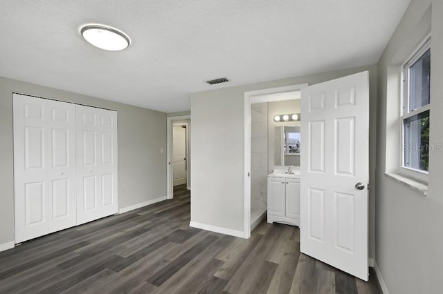 7625 Marechal Ave, Port Richey, FL 34668 - unfurnished bedroom with dark wood-type flooring, a closet, ensuite bath, and a textured ceiling