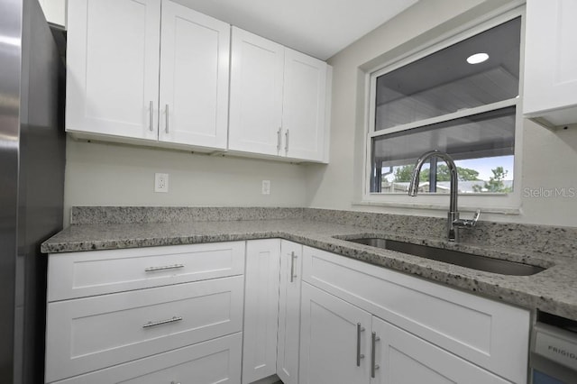 7625 Marechal Ave, Port Richey, FL 34668 - kitchen featuring white cabinetry, light stone countertops, and freestanding refrigerator