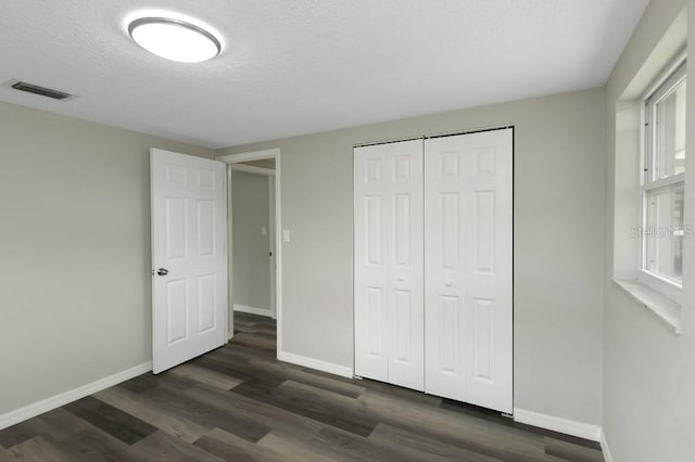 7625 Marechal Ave, Port Richey, FL 34668 - unfurnished bedroom with dark wood-style floors, a textured ceiling, and a closet