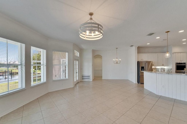 5205 Brighton Shore Dr, Apollo Beach, FL 33572 - unfurnished living room featuring a chandelier, arched walkways, light tile patterned floors, recessed lighting, and crown molding