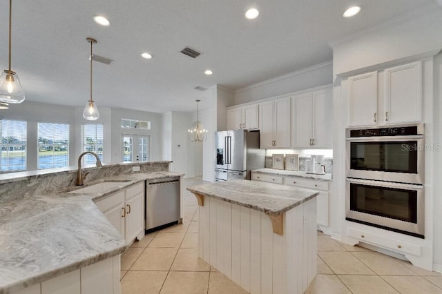 5205 Brighton Shore Dr, Apollo Beach, FL 33572 - kitchen with appliances with stainless steel finishes, ornamental molding, light tile patterned flooring, white cabinets, and recessed lighting