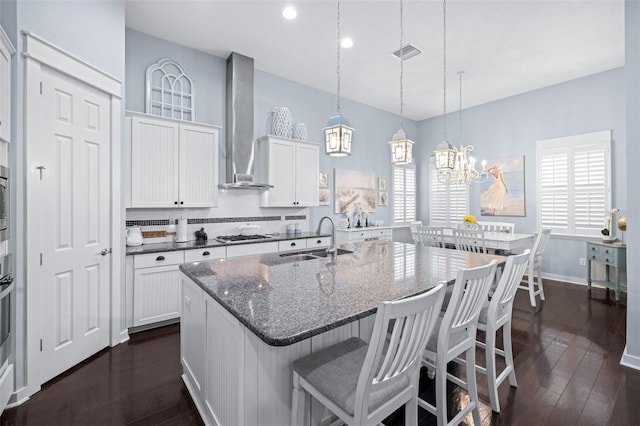 511 Winterside Dr, Apollo Beach, FL 33572 - kitchen with wall chimney exhaust hood, dark wood-style floors, a kitchen island with sink, a breakfast bar, and white cabinets