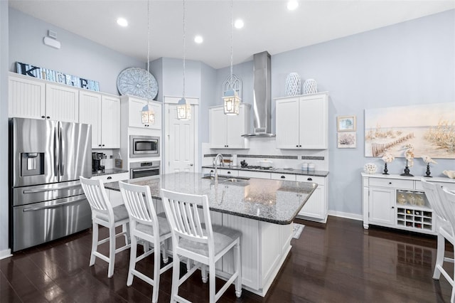 511 Winterside Dr, Apollo Beach, FL 33572 - kitchen featuring appliances with stainless steel finishes, wall chimney range hood, a center island with sink, white cabinets, and dark wood-type flooring