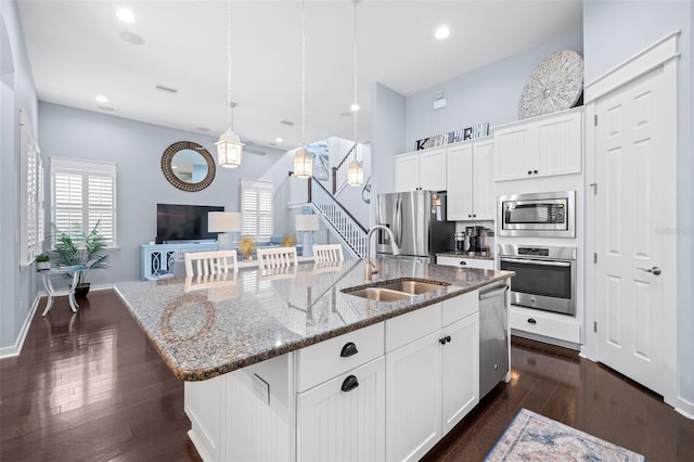 511 Winterside Dr, Apollo Beach, FL 33572 - kitchen featuring appliances with stainless steel finishes, a kitchen island with sink, dark wood-style floors, stone countertops, and healthy amount of natural light