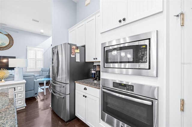 511 Winterside Dr, Apollo Beach, FL 33572 - kitchen featuring stainless steel appliances, dark stone counters, white cabinets, and dark wood finished floors