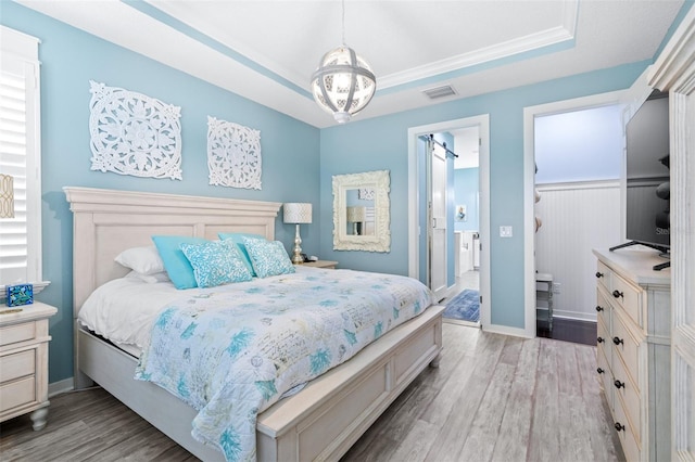 511 Winterside Dr, Apollo Beach, FL 33572 - bedroom with wood finished floors, a tray ceiling, and ensuite bathroom