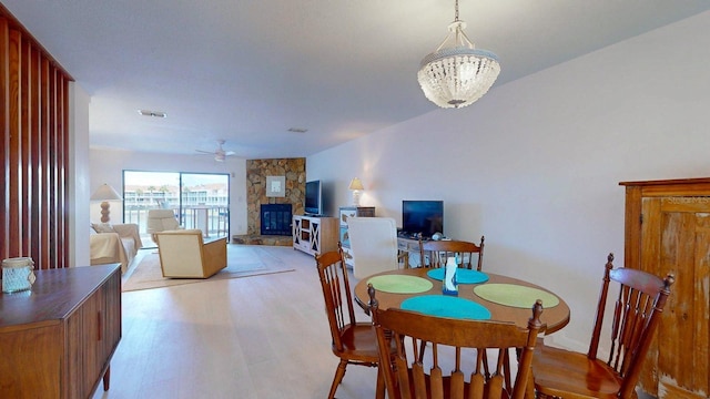 12132 Capri Cir S, Treasure Island, FL 33706 - dining space with a stone fireplace, light wood-style flooring, and a ceiling fan