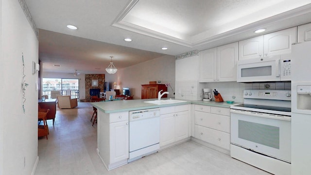 12132 Capri Cir S, Treasure Island, FL 33706 - kitchen featuring white appliances, a peninsula, white cabinetry, recessed lighting, and light countertops