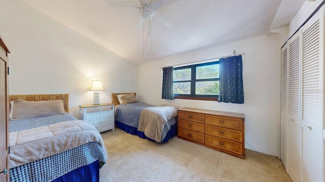 12132 Capri Cir S, Treasure Island, FL 33706 - bedroom featuring light colored carpet, a closet, vaulted ceiling, a textured ceiling, and a ceiling fan