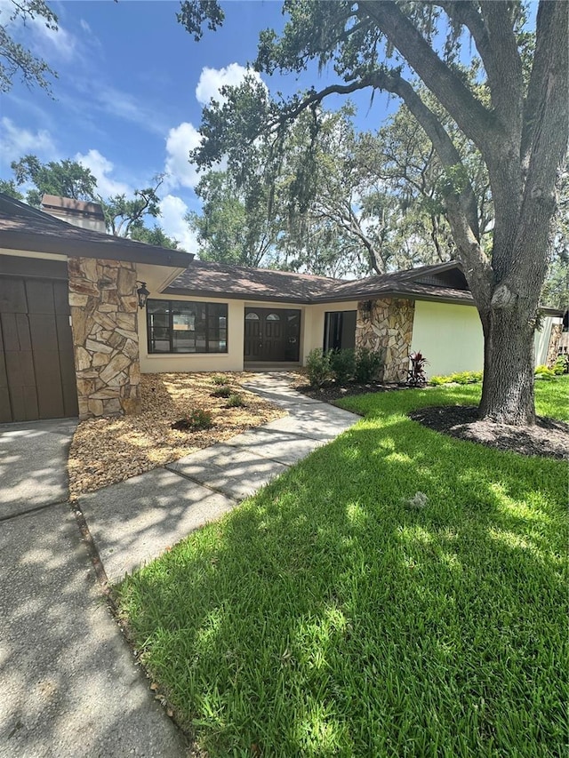 2102 Doefield Ct, Valrico, FL 33596 - view of front of house featuring stone siding, a front yard, and concrete driveway