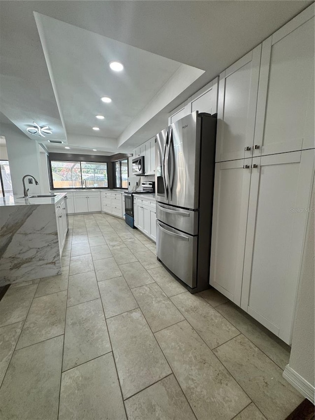 2102 Doefield Ct, Valrico, FL 33596 - kitchen with appliances with stainless steel finishes, a tray ceiling, white cabinets, and recessed lighting
