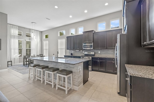 7114 Bowspirit Pl, Apollo Beach, FL 33572 - kitchen featuring stainless steel appliances, light tile patterned floors, a kitchen breakfast bar, recessed lighting, and light stone counters