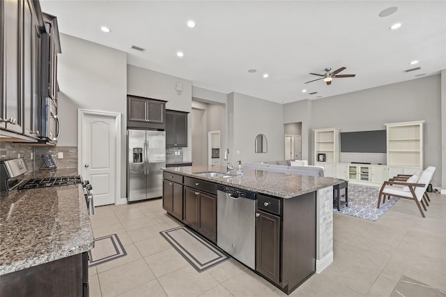 7114 Bowspirit Pl, Apollo Beach, FL 33572 - kitchen with appliances with stainless steel finishes, a ceiling fan, light tile patterned floors, an island with sink, and decorative backsplash