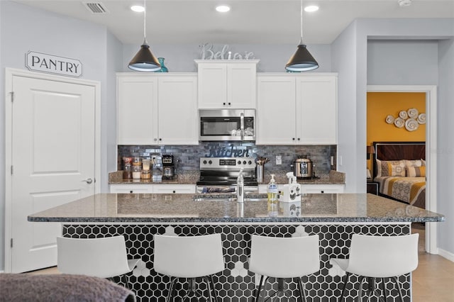 13301 Waterleaf Garden Cir, Riverview, FL 33579 - kitchen with stainless steel appliances, decorative backsplash, a kitchen island with sink, white cabinets, and recessed lighting