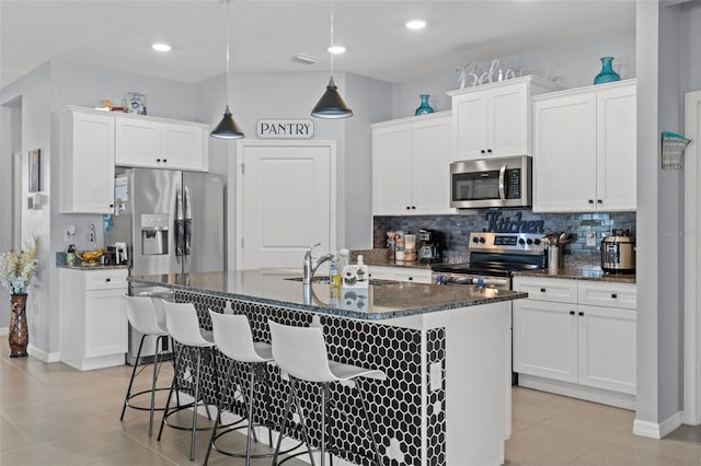 13301 Waterleaf Garden Cir, Riverview, FL 33579 - kitchen with appliances with stainless steel finishes, light tile patterned floors, tasteful backsplash, a kitchen breakfast bar, and white cabinetry