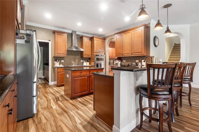 165 Mobbly Bay Dr, Oldsmar, FL 34677 - kitchen with wall chimney range hood, stainless steel appliances, arched walkways, a peninsula, and a kitchen breakfast bar