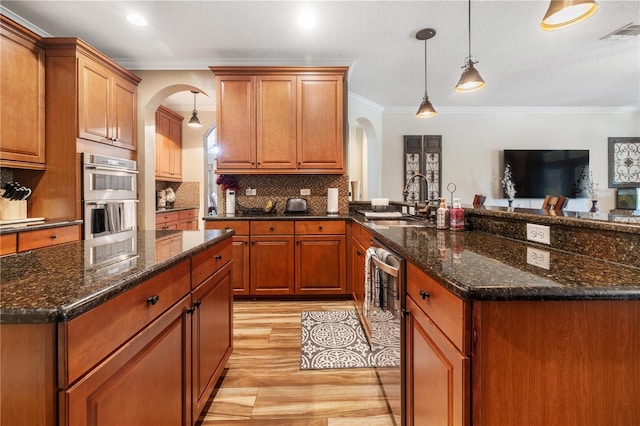 165 Mobbly Bay Dr, Oldsmar, FL 34677 - kitchen with arched walkways, appliances with stainless steel finishes, light wood finished floors, crown molding, and a peninsula