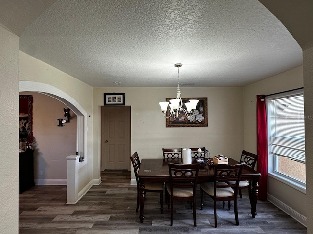 701 N 7th St, Haines City, FL 33844 - dining area with arched walkways, wood finished floors, a textured ceiling, and a chandelier