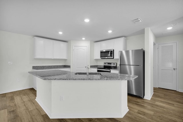 103 Whippoorwill Dr, Palm Coast, FL 32164 - kitchen featuring stainless steel appliances, wood finished floors, white cabinets, light stone countertops, and recessed lighting