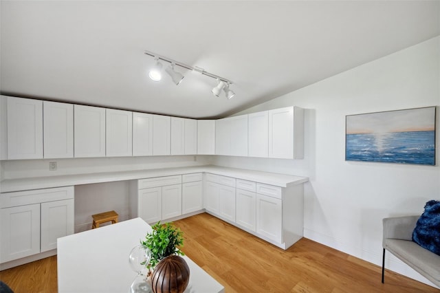 21906 Shamu Dr, Land O Lakes, FL 34639 - kitchen with track lighting, vaulted ceiling, white cabinetry, light wood finished floors, and light countertops