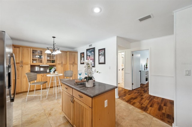 21906 Shamu Dr, Land O Lakes, FL 34639 - kitchen with stainless steel fridge, dark countertops, glass insert cabinets, a chandelier, and hanging light fixtures