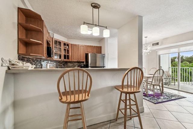 3315 58th Ave S Unit 311, Saint Petersburg, FL 33712 - kitchen with freestanding refrigerator, a textured ceiling, brown cabinetry, backsplash, and glass insert cabinets