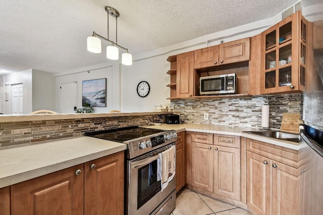 3315 58th Ave S Unit 311, Saint Petersburg, FL 33712 - kitchen with stainless steel appliances, a textured ceiling, light countertops, backsplash, and glass insert cabinets