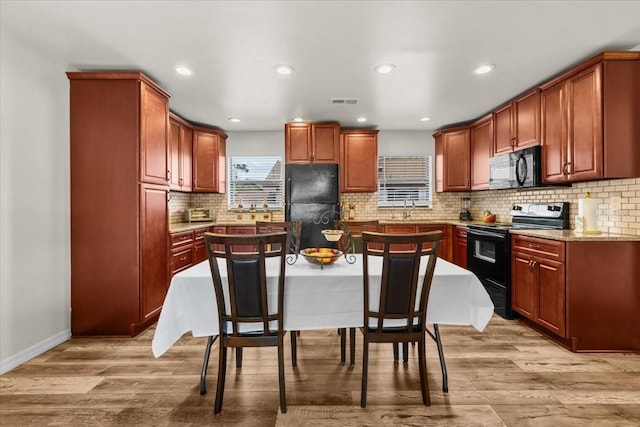 4945 91st Ave N Unit 30, Pinellas Park, FL 33782 - kitchen with black appliances, light wood finished floors, backsplash, recessed lighting, and light stone countertops
