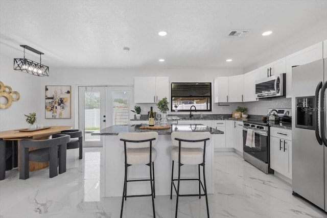 6370 Elmhurst Dr, Pinellas Park, FL 33782 - kitchen with stainless steel appliances, a kitchen breakfast bar, light marble finish floors, white cabinetry, and recessed lighting