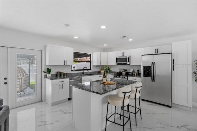 6370 Elmhurst Dr, Pinellas Park, FL 33782 - kitchen with stainless steel appliances, a breakfast bar, light marble finish floors, white cabinets, and recessed lighting