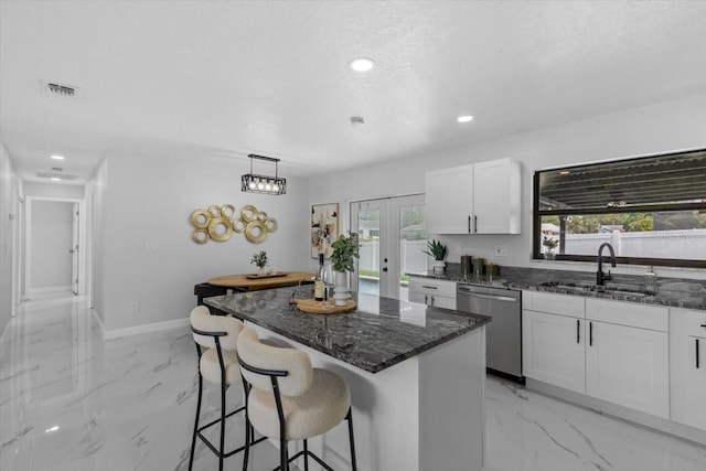 6370 Elmhurst Dr, Pinellas Park, FL 33782 - kitchen with stainless steel dishwasher, light marble finish floors, dark stone countertops, a kitchen bar, and white cabinetry