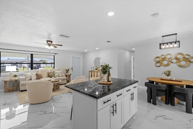 6370 Elmhurst Dr, Pinellas Park, FL 33782 - kitchen featuring light marble finish floors, a kitchen island, white cabinets, recessed lighting, and dark stone counters