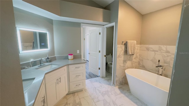 28826 Windover St, Wesley Chapel, FL 33545 - full bathroom featuring marble look tiles, a freestanding tub, vanity, tile walls, and wainscoting