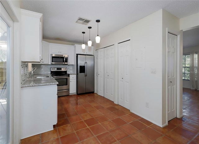 945 Hamilton Ct, Palm Harbor, FL 34683 - kitchen featuring stainless steel appliances, white cabinetry, tasteful backsplash, pendant lighting, and dark tile patterned flooring