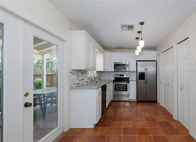 945 Hamilton Ct, Palm Harbor, FL 34683 - kitchen with stainless steel appliances, decorative backsplash, white cabinets, pendant lighting, and light stone countertops