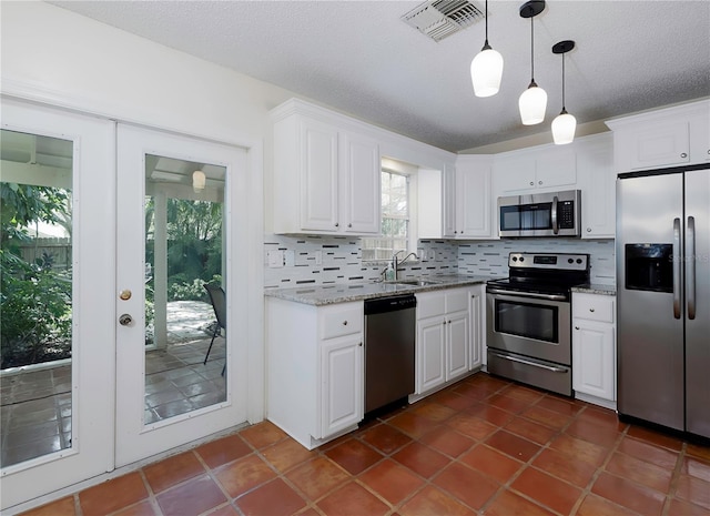 945 Hamilton Ct, Palm Harbor, FL 34683 - kitchen with appliances with stainless steel finishes, tasteful backsplash, white cabinets, hanging light fixtures, and a textured ceiling