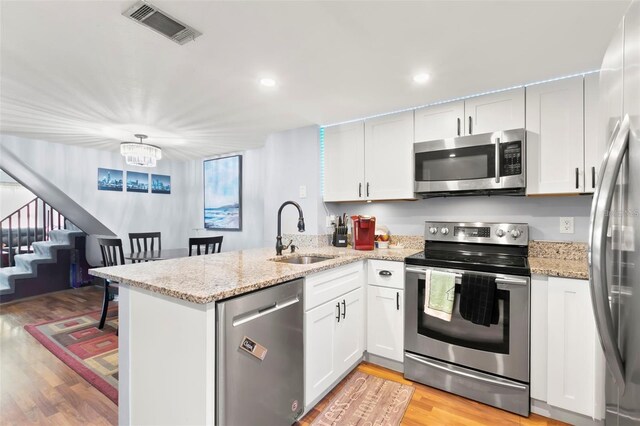 6681 121st Ave Unit I, Largo, FL 33773 - kitchen with stainless steel appliances, a peninsula, light wood-type flooring, white cabinetry, and recessed lighting