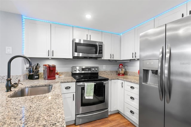 6681 121st Ave Unit I, Largo, FL 33773 - kitchen with stainless steel appliances, white cabinets, light stone counters, light wood finished floors, and recessed lighting