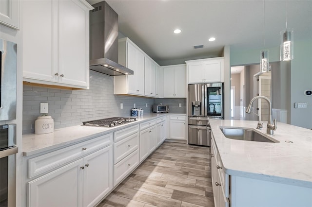12652 Shetland Walk Dr, Lithia, FL 33547 - kitchen with wall chimney exhaust hood, stainless steel appliances, light wood-style flooring, white cabinetry, and decorative backsplash