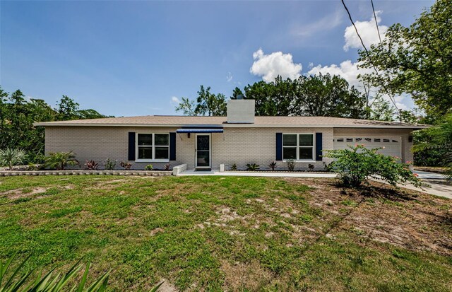 7332 Janczlik Dr, New Port Richey, FL 34652 - view of front of house with brick siding, a garage, a front lawn, a chimney, and driveway