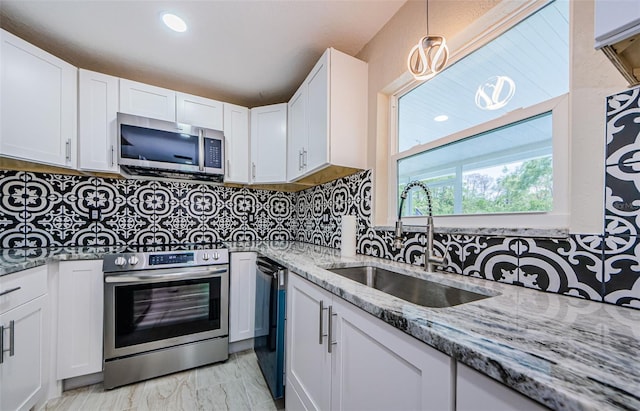 7332 Janczlik Dr, New Port Richey, FL 34652 - kitchen featuring appliances with stainless steel finishes, white cabinetry, light stone countertops, decorative backsplash, and pendant lighting