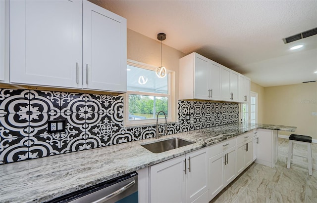 7332 Janczlik Dr, New Port Richey, FL 34652 - kitchen featuring stainless steel dishwasher, white cabinetry, backsplash, light marble finish floors, and a textured ceiling