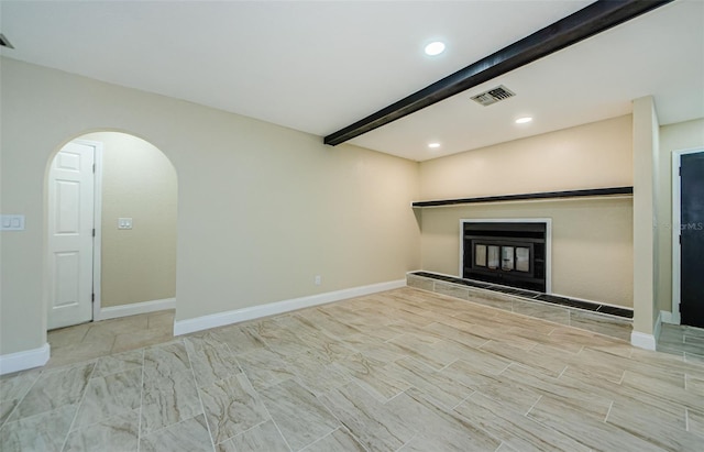 7332 Janczlik Dr, New Port Richey, FL 34652 - unfurnished living room featuring arched walkways, a glass covered fireplace, recessed lighting, and beam ceiling