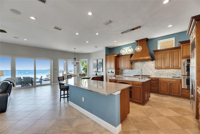 6418 Bright Bay Ct, Apollo Beach, FL 33572 - kitchen with a large island, brown cabinets, premium range hood, and recessed lighting