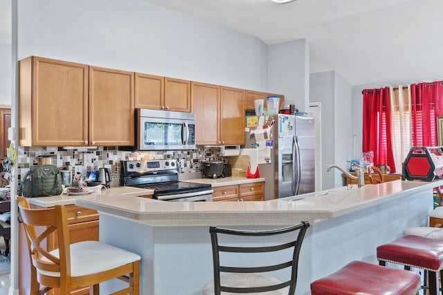 1955 Manatee Ct, Kissimmee, FL 34759 - kitchen featuring stainless steel appliances, light countertops, a breakfast bar area, backsplash, and a peninsula