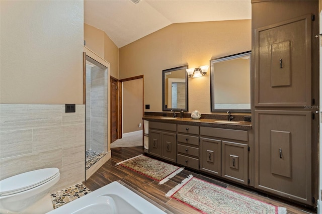 10053 W Bay St, Seminole, FL 33776 - bathroom with lofted ceiling, double vanity, wood finished floors, a tile shower, and tile walls
