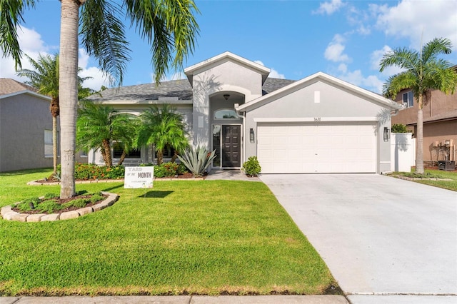 1631 Shady Oaks Dr, Oldsmar, FL 34677 - view of front of house featuring stucco siding, a garage, driveway, and a front lawn