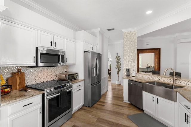 1631 Shady Oaks Dr, Oldsmar, FL 34677 - kitchen with appliances with stainless steel finishes, ornamental molding, decorative backsplash, light wood-type flooring, and white cabinetry