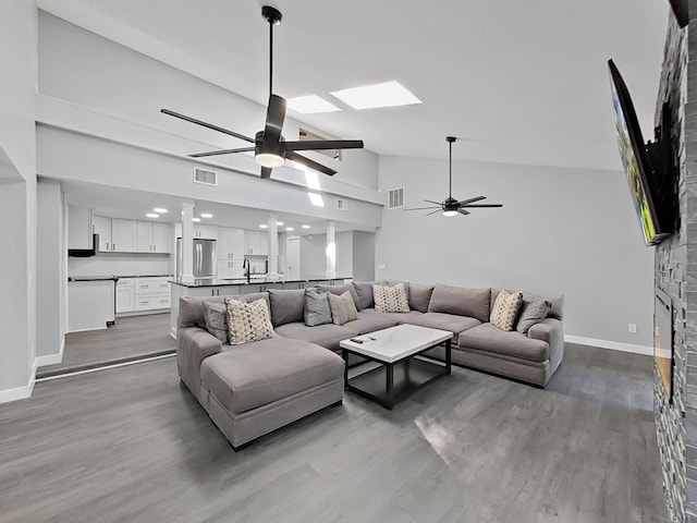852 Village Way, Palm Harbor, FL 34683 - living room with ceiling fan, lofted ceiling, wood finished floors, a skylight, and a fireplace
