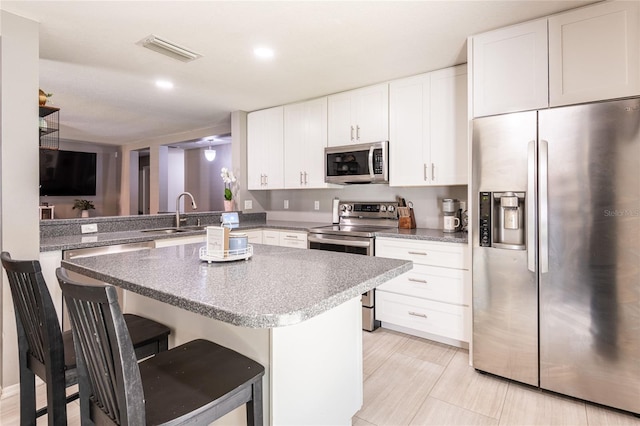 4132 Festival Pointe Blvd, Mulberry, FL 33860 - kitchen with appliances with stainless steel finishes, a center island, a breakfast bar, white cabinetry, and recessed lighting